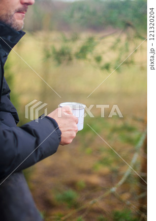 Man Holding a white Mug Outdoors in Nature with a Peaceful Background. High quality photo 121320204