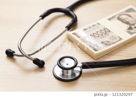 机に置かれた聴診器と100万円 121320297