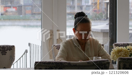 Front view of old senior asian woman sitting at dining table in a comfortable home 121320606