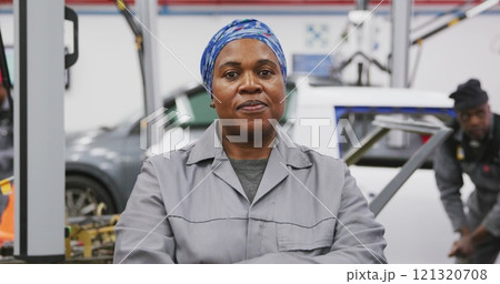 Portrait of an African American female car mechanic working in a township workshop, crossing her arm 121320708
