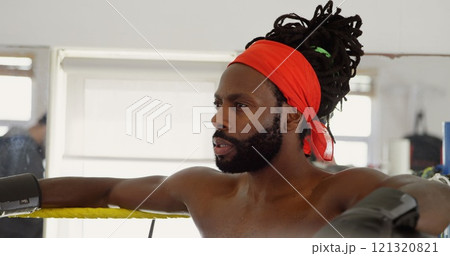 Male boxer relaxing in boxing ring at fitness studio 121320821