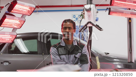 Portrait of an African American male car mechanic working in a township workshop, crossing his arms 121320850