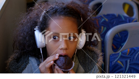 Girl commuter having muffin while travelling in bus Girl commuter having muffin while travelling in bus 121321449