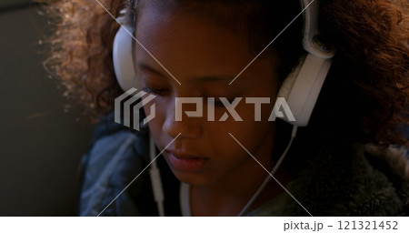 Close-up of girl listening music while travelling in bus Close-up of girl listening music while travelling in bus 121321452