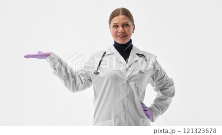 Confident young woman, doctor with stethoscope posing raising hand as she demonstrate something against white studio background. Confident young woman, doctor with stethoscope posing raising hand as she demonstrate something against white studio background. 121323678