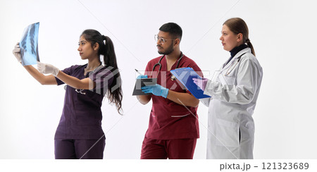 Three medical professionals, working in team and reviewing X-ray against white studio background. Medical check-up and treatments. Three medical professionals, working in team and reviewing X-ray against white studio background. Medical check-up and treatments. 121323689