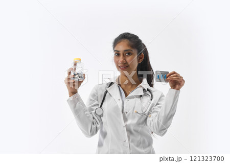 Cheerful, young medical worker showing blister of pills and bottle of vitamins or diet supplements against white studio background. healthcare 121323700