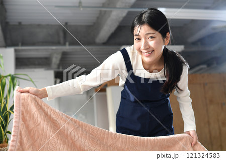 ベッドメイキングをするエプロン姿の女性 121324583