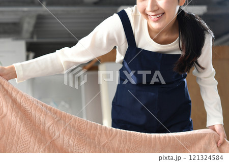 ベッドメイキングをするエプロン姿の女性 121324584