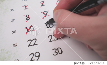 A hand marking important dates on a calendar, showing effective time management and organization skills A hand marking important dates on a calendar, showing effective time management and organization skills 121324734