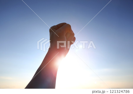 Rising sunrise sun background, brilliant sunlight shining through arms clenched and outstretched toward the sky, symbolizing powerful new year wishes, resolutions, challenges and departures Rising sunrise sun background, brilliant sunlight shining through arms clenched and outstretched toward the sky, symbolizing powerful new year wishes, resolutions, challenges and departures 121324786