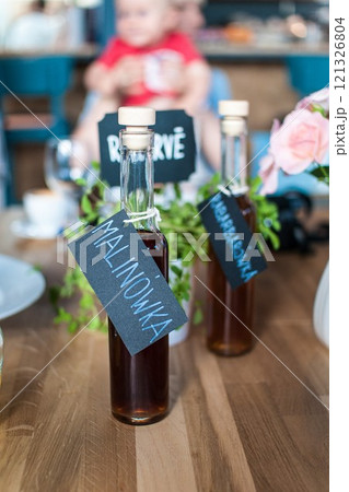 Raspberry liqueur in a glass bottle with a label stands on a wooden table 121326804