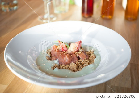 Crumble with a rhubarb and English mint sauce placed on white plate 121326806