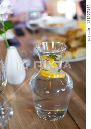 Homemade lemonade with fresh lemon and mint in a glass vase lit by daylight 121327152