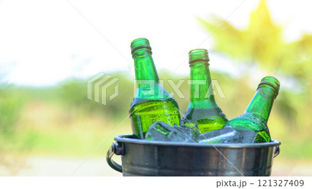 Green beer bottle rest in a bucket of ice, symbolizing refreshment and relaxation, perfect for unwinding during social gatherings or celebrating special moments. 121327409