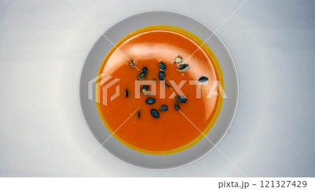 Creamy orange pumpkin soup with seeds served on a table. Creamy orange pumpkin soup with seeds served on a table. 121327429