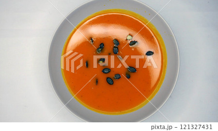 Creamy orange pumpkin soup with seeds served on a table. 121327431