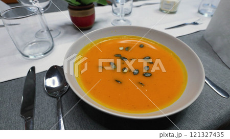 Creamy orange pumpkin soup with seeds served on a table. 121327435