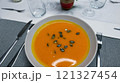 Creamy orange pumpkin soup with seeds served on a table. 121327454