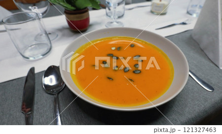 Creamy orange pumpkin soup with seeds served on a table. 121327463