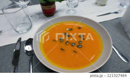 Creamy orange pumpkin soup with seeds served on a table. 121327464