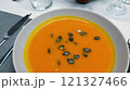 Creamy orange pumpkin soup with seeds served on a table. 121327466