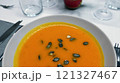 Creamy orange pumpkin soup with seeds served on a table. 121327467