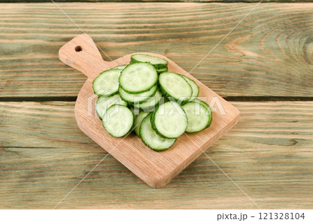 Fresh cucumber sliced into circles on a wooden cutting board. 121328104