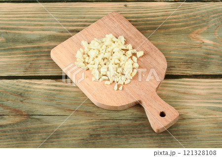 Finely chopped ginger root on a wooden cutting board. 121328108