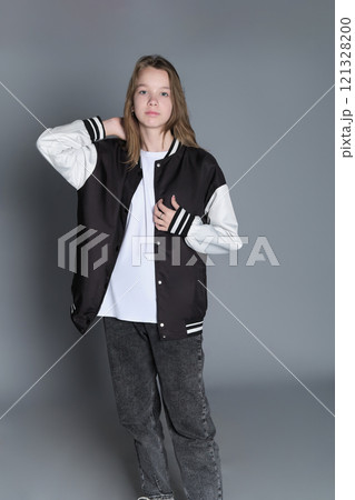 A teenage girl in profile with a varsity jacket resting on her shoulder, giving off a relaxed vibe. Her natural expression highlights youthful energy and individuality. A teenage girl in profile with a varsity jacket resting on her shoulder, giving off a relaxed vibe. Her natural expression highlights youthful energy and individuality. 121328200