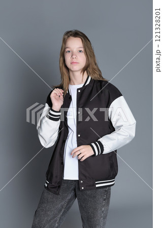 A teenage girl in profile with a varsity jacket resting on her shoulder, giving off a relaxed vibe. Her natural expression highlights youthful energy and individuality. 121328201