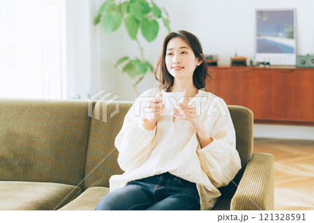ソファに座ってコーヒーを飲む女性 121328591