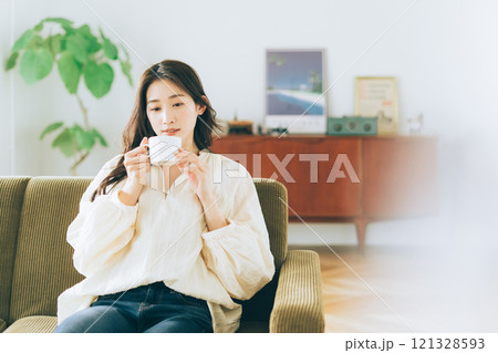 ソファに座ってコーヒーを飲む女性 121328593