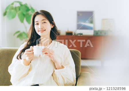 ソファに座ってコーヒーを飲む女性 121328596
