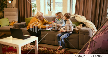 Grandmother guiding girl to check dog's ear with medical tools, teaching care for others, boy watches, learning about responsibility and health basics. 121328658