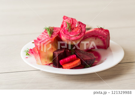 pickled cabbage with beets and carrots, in a plate, on a wooden table pickled cabbage with beets and carrots, in a plate, on a wooden table 121329988