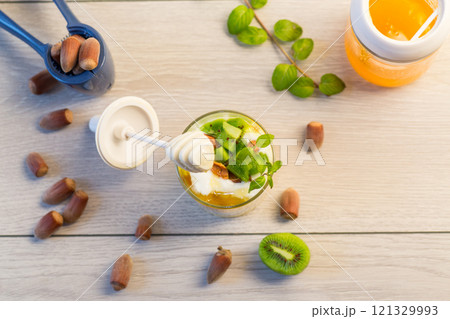 homemade yogurt with kiwi, honey and nuts in a glass on a wooden table homemade yogurt with kiwi, honey and nuts in a glass on a wooden table 121329993