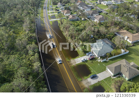 Flooded american street with moving vehicles and surrounded with water houses in Florida residential area. Consequences of hurricane natural disaster Flooded american street with moving vehicles and surrounded with water houses in Florida residential area. Consequences of hurricane natural disaster 121330339