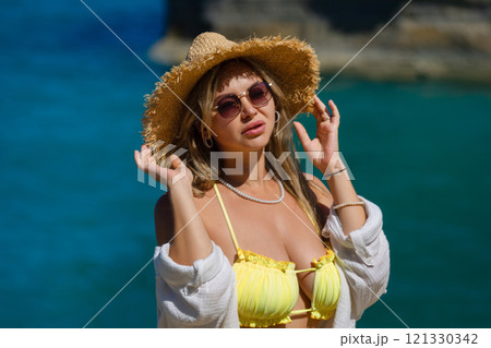 Blonde woman with big breasts in a yellow swimsuit on the beach. Portrait of a young woman with a beautiful body. Sexy model showing bra Blonde woman with big breasts in a yellow swimsuit on the beach. Portrait of a young woman with a beautiful body. Sexy model showing bra 121330342