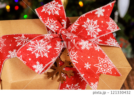 Lovely gift wrapped in red fabric with white snowflakes decorative bow, perfect for merry Christmas holidays 121330432