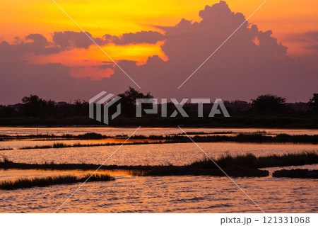 A breathtaking sunset casts a warm glow over a flooded rice field. A breathtaking sunset casts a warm glow over a flooded rice field. 121331068