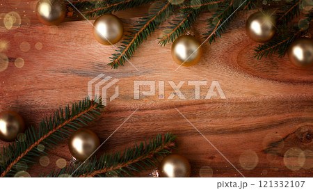 New Year's background made of wood with a Christmas tree branch and framed by New Year's baubles. New Year's background made of wood with a Christmas tree branch and framed by New Year's baubles. 121332107