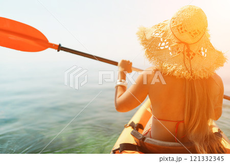 Woman in kayak back view. Happy woman with long hair in a swimsuit and hat floating in kayak on the sea. Summer holiday vacation. Summer holidays vacation at sea. Woman in kayak back view. Happy woman with long hair in a swimsuit and hat floating in kayak on the sea. Summer holiday vacation. Summer holidays vacation at sea. 121332345