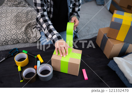 Girl Packing A Cardboard Box At Home And Preparing Packages For Shipping Girl Packing A Cardboard Box At Home And Preparing Packages For Shipping 121332470