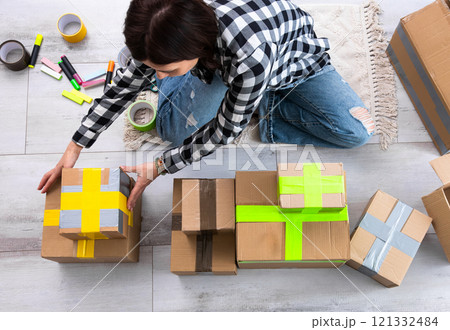 Girl Packs Cardboard Boxes And Seals Them With Tape At Home As She Prepares Them For Delivery 121332484
