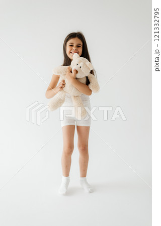 Cute little girl in pajama hugging her toy. happy childhood concept, indoor studio portrait Cute little girl in pajama hugging her toy. happy childhood concept, indoor studio portrait 121332795