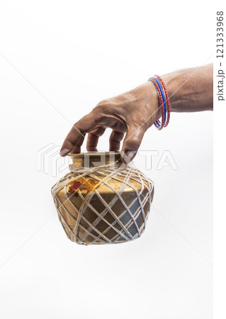 Hand holding a brass jar decorated with ethnic significance, Closeup 121333968