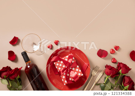 Valentine's day border with red plate, chocolate sweets, romantic gift, wine and red roses on beige background. View from above. Valentine's day border with red plate, chocolate sweets, romantic gift, wine and red roses on beige background. View from above. 121334388