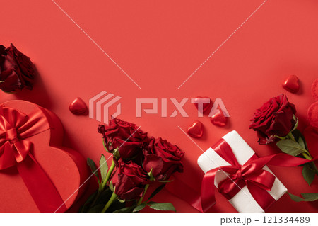 Valentine's day card with gift, hearts and red roses on red background. View from above. Copy space. Romantic date concept. Greeting card. 121334489