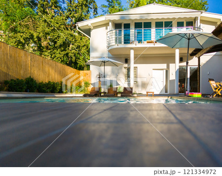 Modern residential house with swimming pool and patio. Luxury outdoor living space surrounded by greenery 121334972